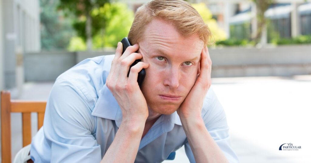 Imagen de un hombre frustrado al teléfono con el texto “¿Solo te llaman agencias?” – Guía de Vía Particular para evitar llamadas de inmobiliarias.